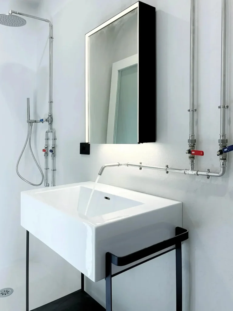 Bagno "stile industriale" con tubazione a vista geberit, con pareti in micro cemento color ghiaccio. Milano ripa di P.ta Ticinese