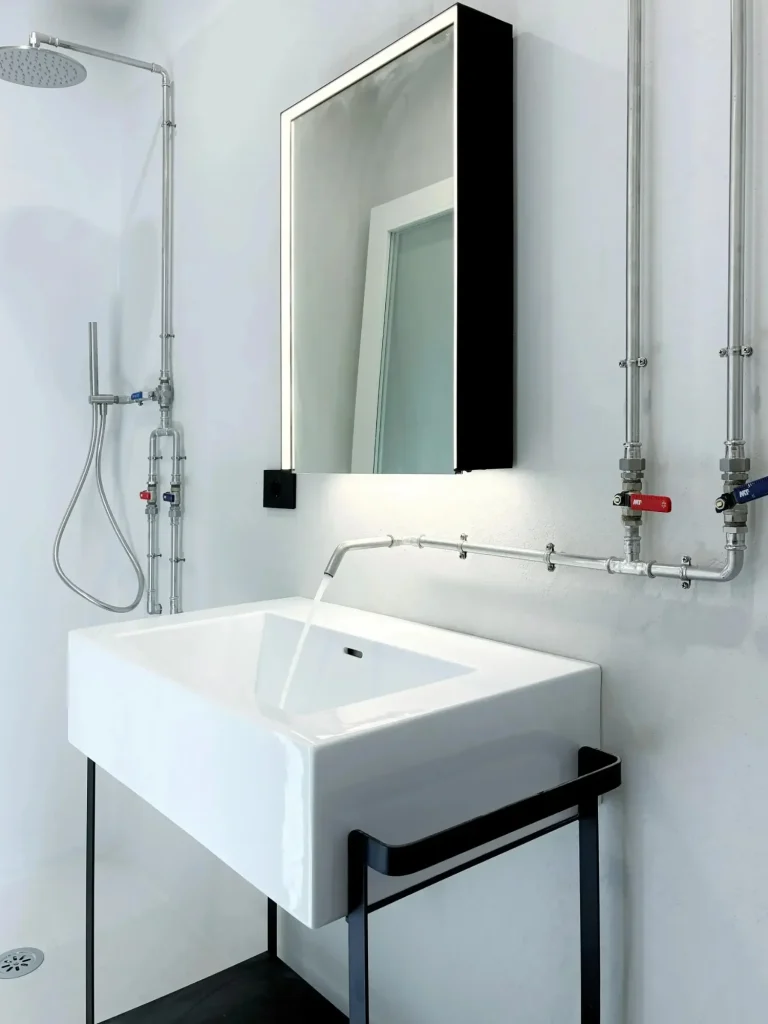 Bagno "stile industriale" con  tubazione a vista geberit, con pareti in micro cemento color ghiaccio. Milano ripa di P.ta Ticinese